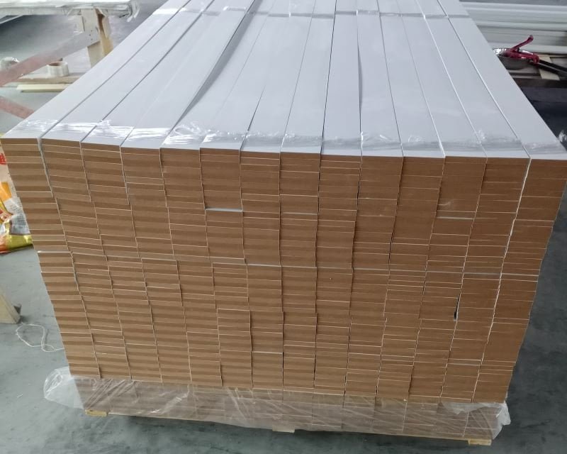 Stacked MDF moulding profiles showing smooth painted white finish with crisp routed edge detail, ready for export packaging