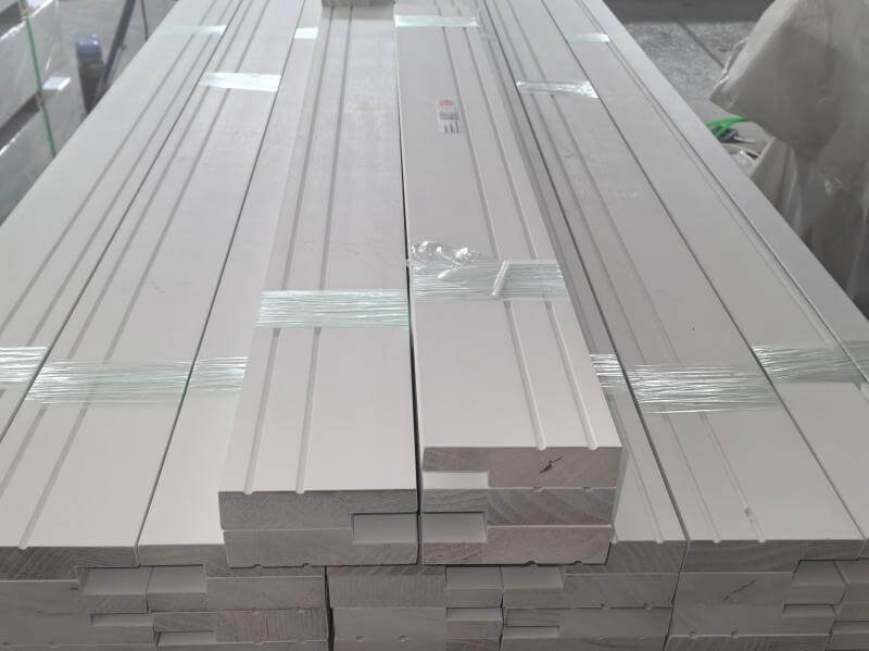 Quality control inspector measuring a wood moulding profile against specification tolerances on the production line